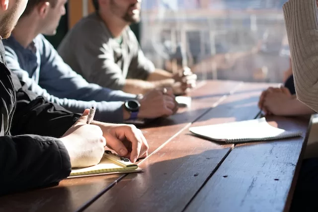 people collaborating by window on notepads